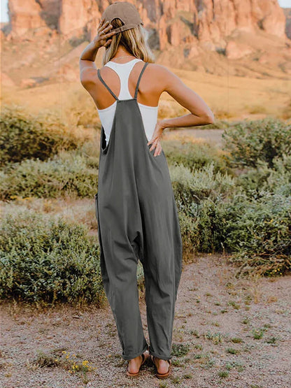 Woman wearing relaxed grey overalls and a white tank top outdoors in a desert landscape