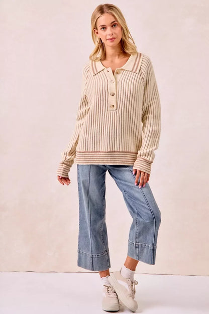 Woman in cream ribbed knit sweater, light blue wide-leg jeans, and beige sneakers