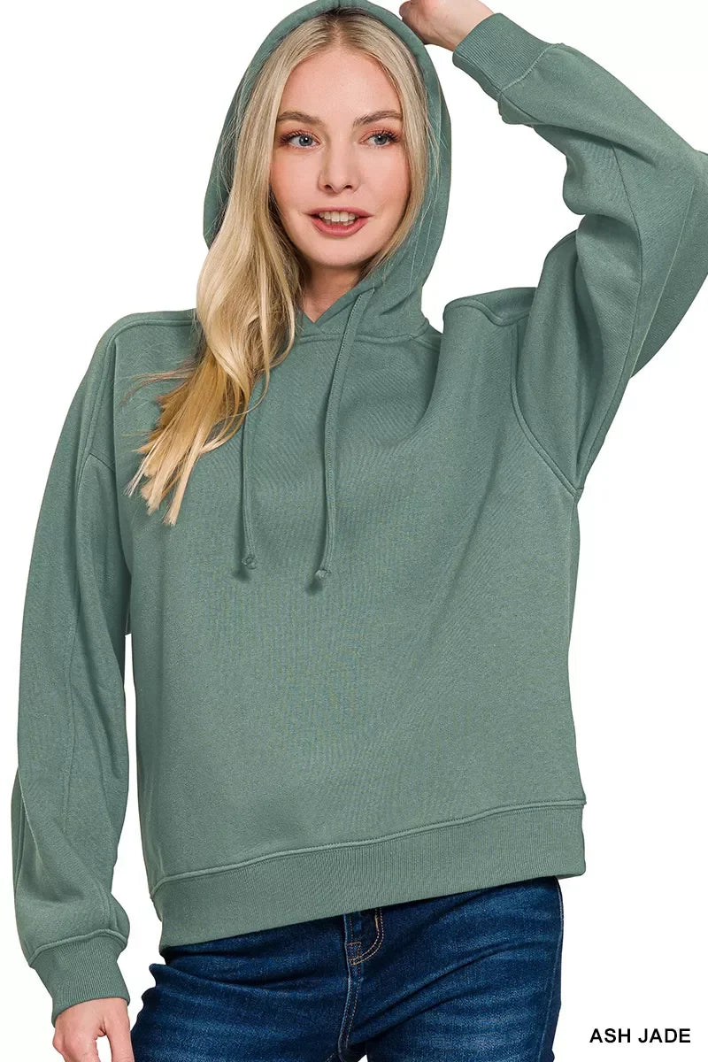 Woman wearing ash jade green hoodie with drawstrings and blue jeans, relaxed fit style.