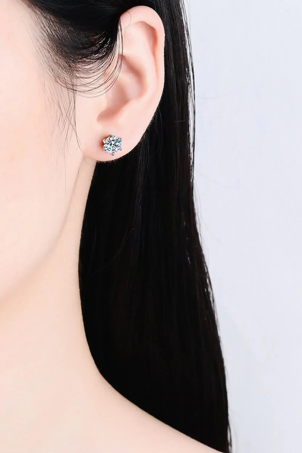 Close-up of a woman's ear wearing a sparkling crystal stud earring