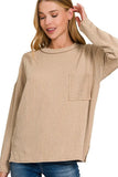 Woman wearing a light mocha ribbed knit long sleeve top with chest pocket and relaxed fit.