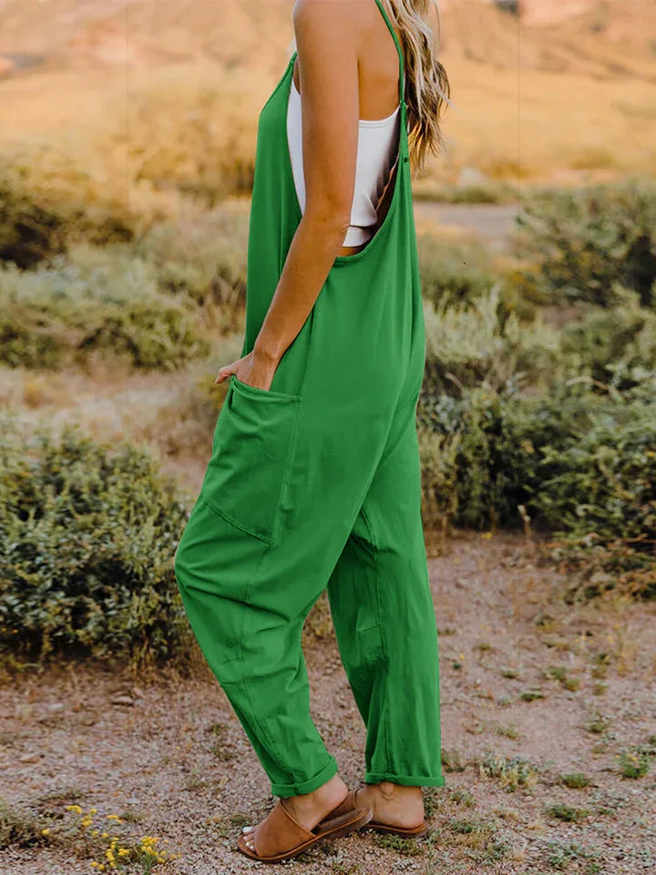 Woman in green relaxed-fit overalls and sandals standing outdoors in nature