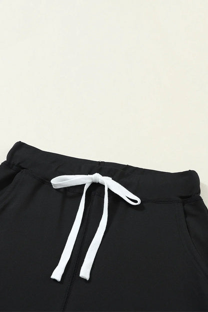 Black jogger pants with white drawstring and elastic waistband on neutral background