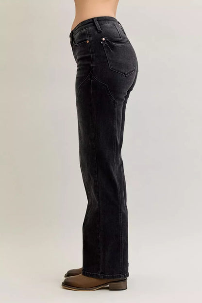 Side view of black high-waisted straight leg jeans with brown boots on a model