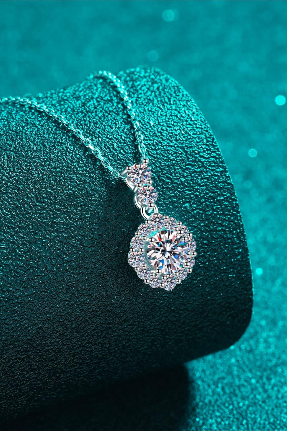 Elegant silver necklace with round crystal pendant on textured teal background