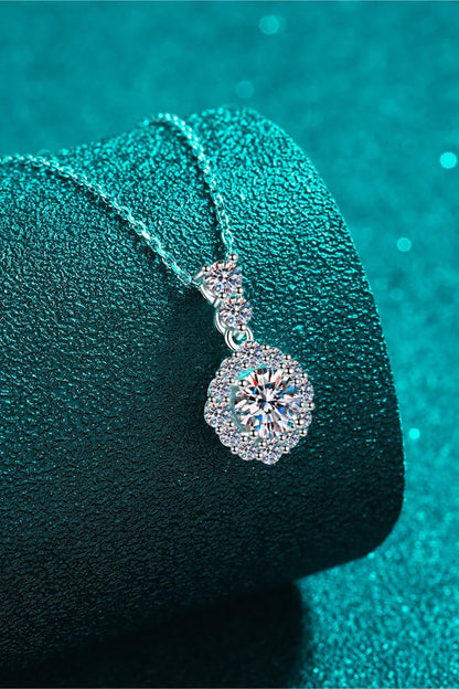 Elegant silver necklace with round crystal pendant on textured teal background
