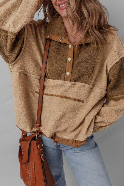 Woman wearing a cozy colorblock sherpa pullover and carrying a brown leather handbag