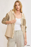 Woman wearing a beige hooded jacket with textured sleeves and front pocket, paired with cargo pants.