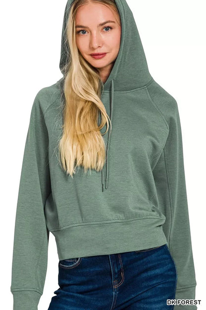Woman wearing a dark forest green hooded sweatshirt with drawstrings and blue jeans