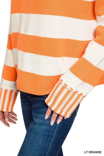 Close-up of a woman wearing a light orange and white striped knit sweater with jeans.