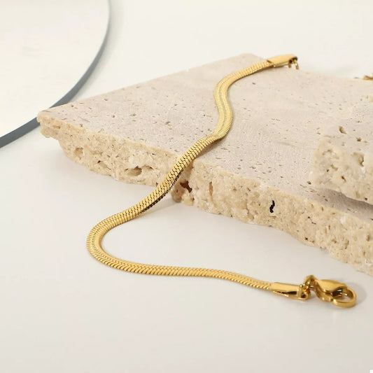 Gold snake chain bracelet displayed on textured stone for modern jewelry styling