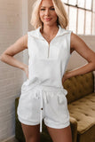 Woman wearing textured white sleeveless zip-up top and matching drawstring shorts