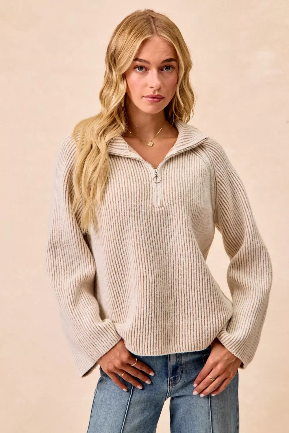Woman wearing a ribbed cream zip collar sweater with relaxed fit and blue jeans