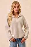 Woman wearing a ribbed cream zip collar sweater with relaxed fit and blue jeans