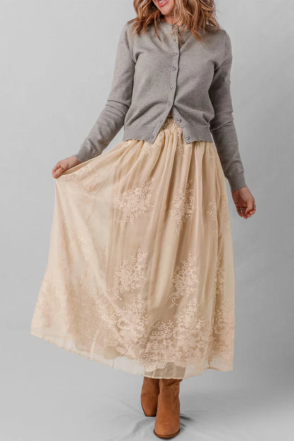 Woman wearing a grey cardigan with a beige lace maxi skirt and brown ankle boots