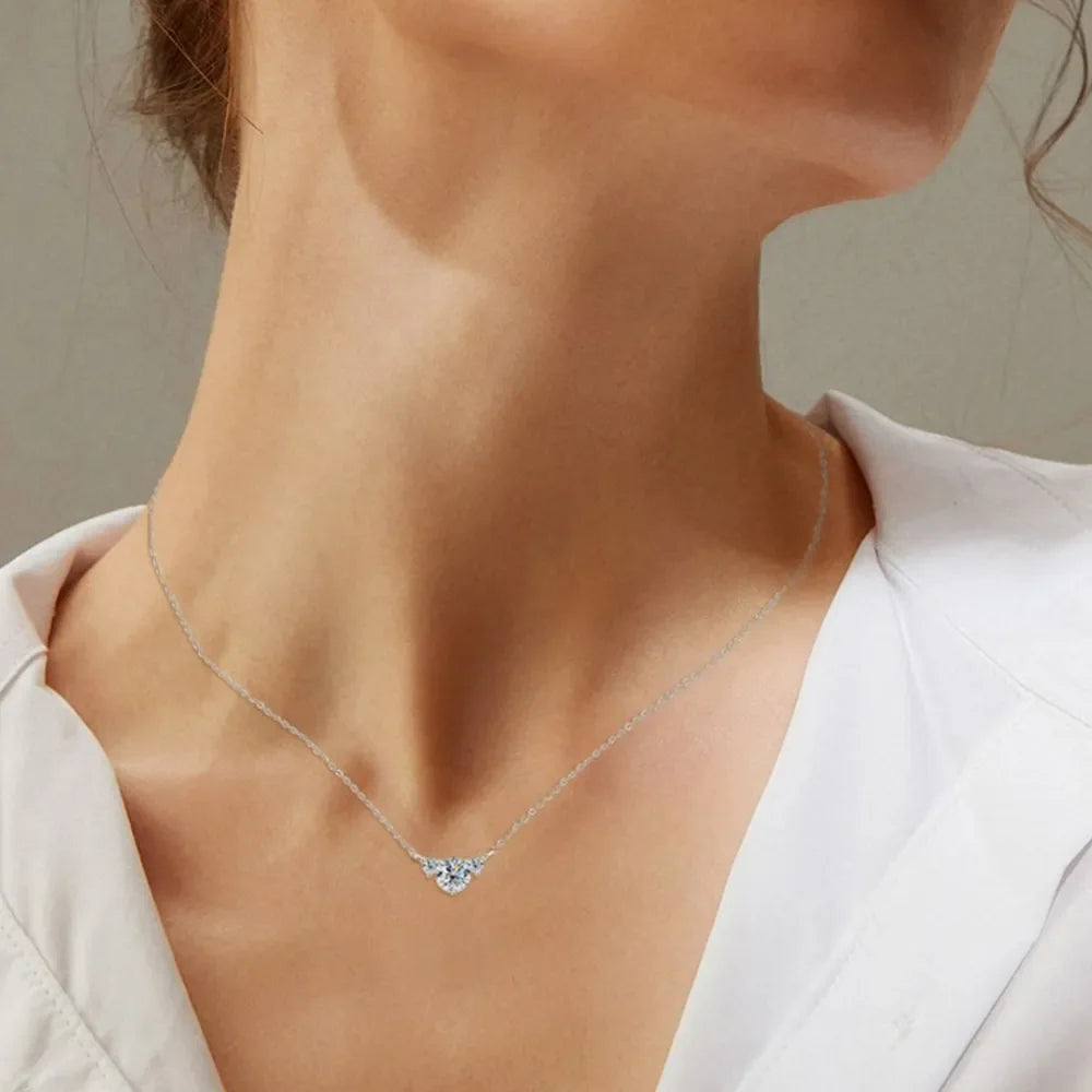 Woman wearing a delicate silver necklace with small crystal pendant, white blouse.