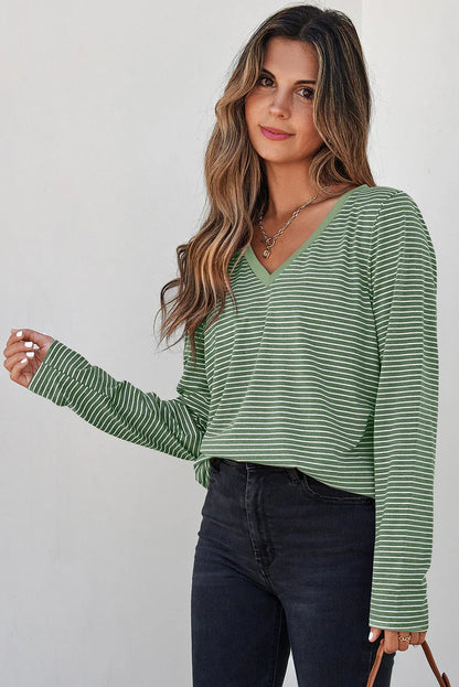 Woman wearing a green striped V-neck long sleeve top with black high-waisted jeans