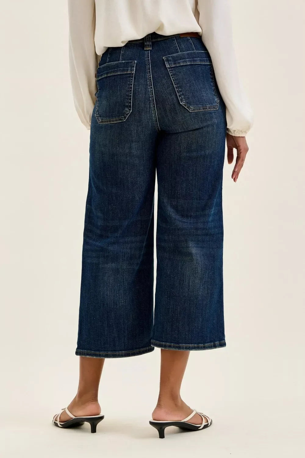 Back view of cropped wide-leg dark wash denim jeans with patch pockets