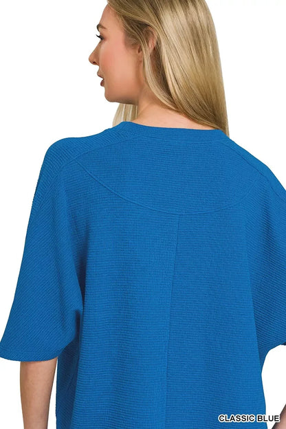 Woman wearing a textured classic blue short-sleeve top, back view, relaxed fit clothing