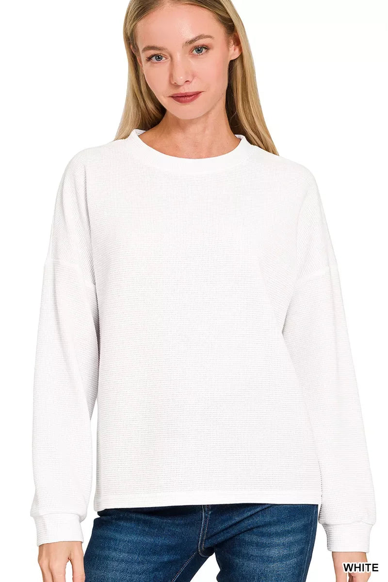 Woman wearing a relaxed-fit white long sleeve waffle knit sweater and blue jeans