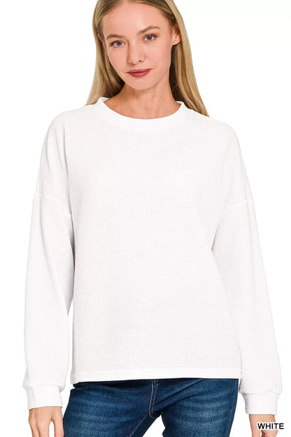 Woman wearing a relaxed-fit white long sleeve waffle knit sweater and blue jeans