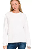 Woman wearing a relaxed-fit white long sleeve waffle knit sweater and blue jeans