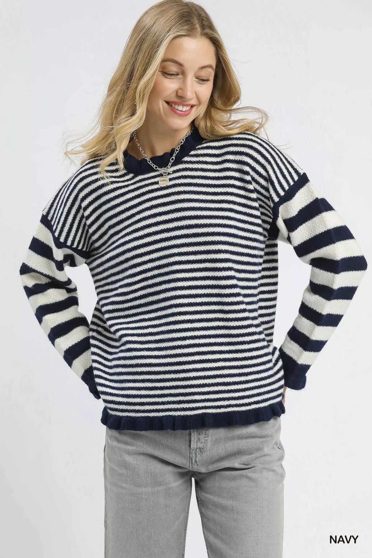 Woman wearing a navy and white striped sweater with relaxed fit and light grey jeans.