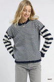 Woman wearing a navy and white striped sweater with relaxed fit and light grey jeans.