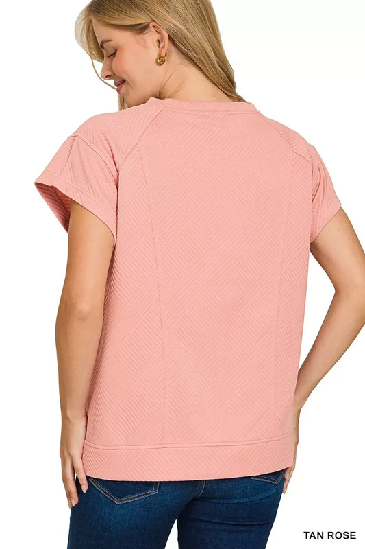 Back view of woman in textured tan rose short sleeve top and blue jeans