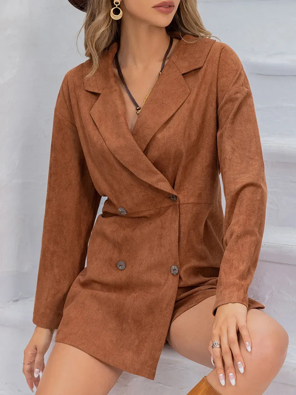 Woman wearing a brown suede double-breasted blazer dress with gold hoop earrings.
