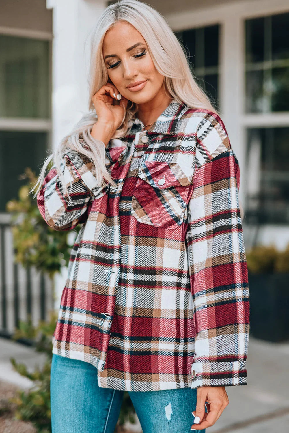 Woman wearing a red plaid shacket with chest pockets and blue jeans outdoors