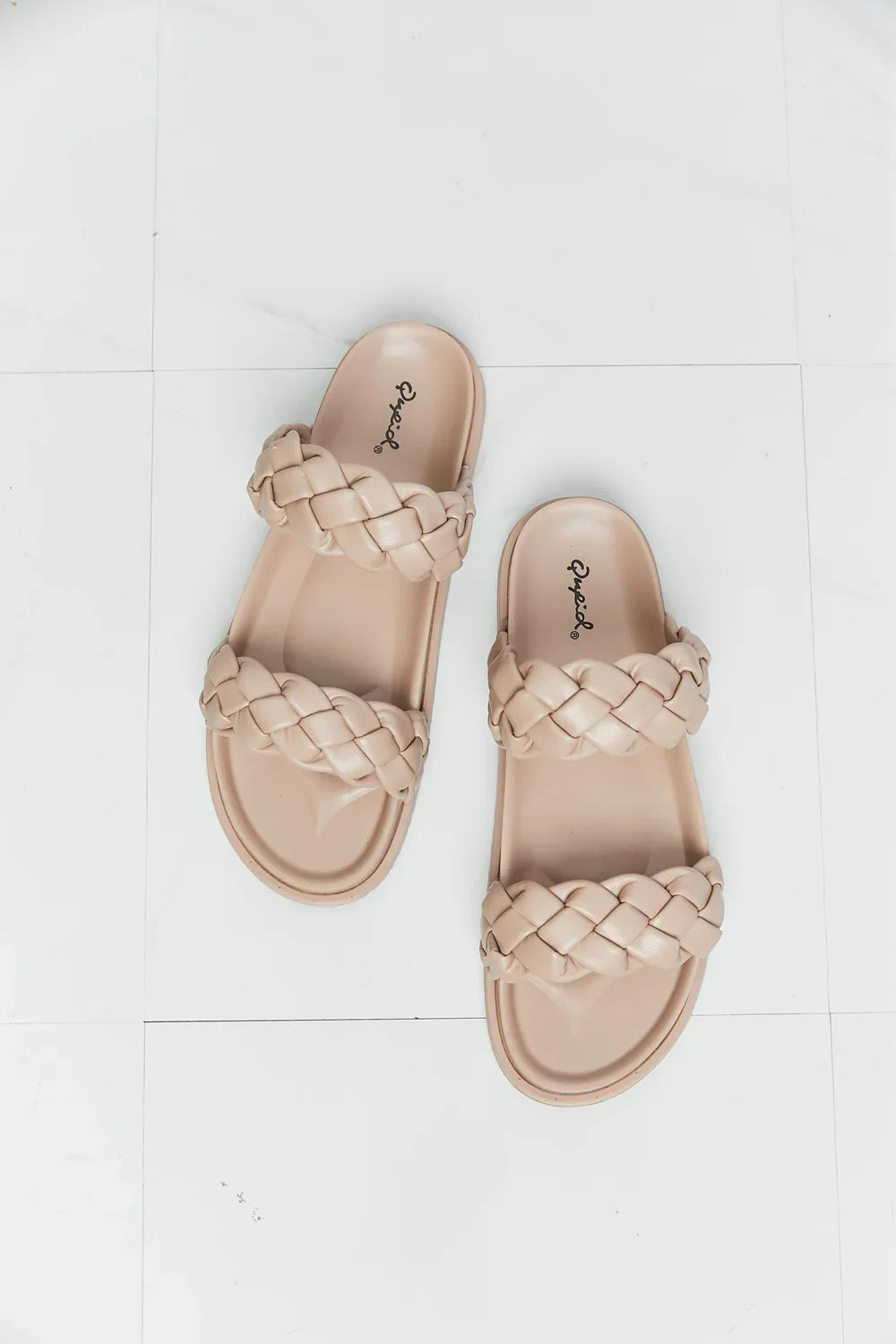 Beige double-braided slide sandals with chunky straps on a white tile background.