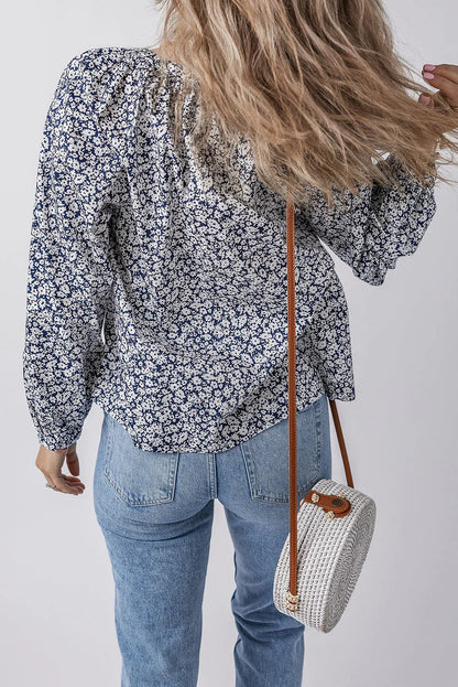 Woman in blue floral blouse and light wash jeans carrying white round woven crossbody bag