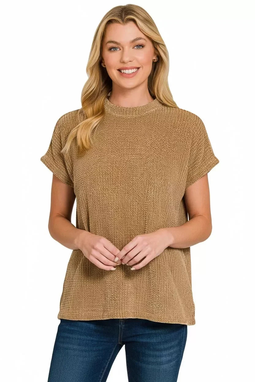 Woman wearing a textured camel short sleeve knit top with jeans on white background