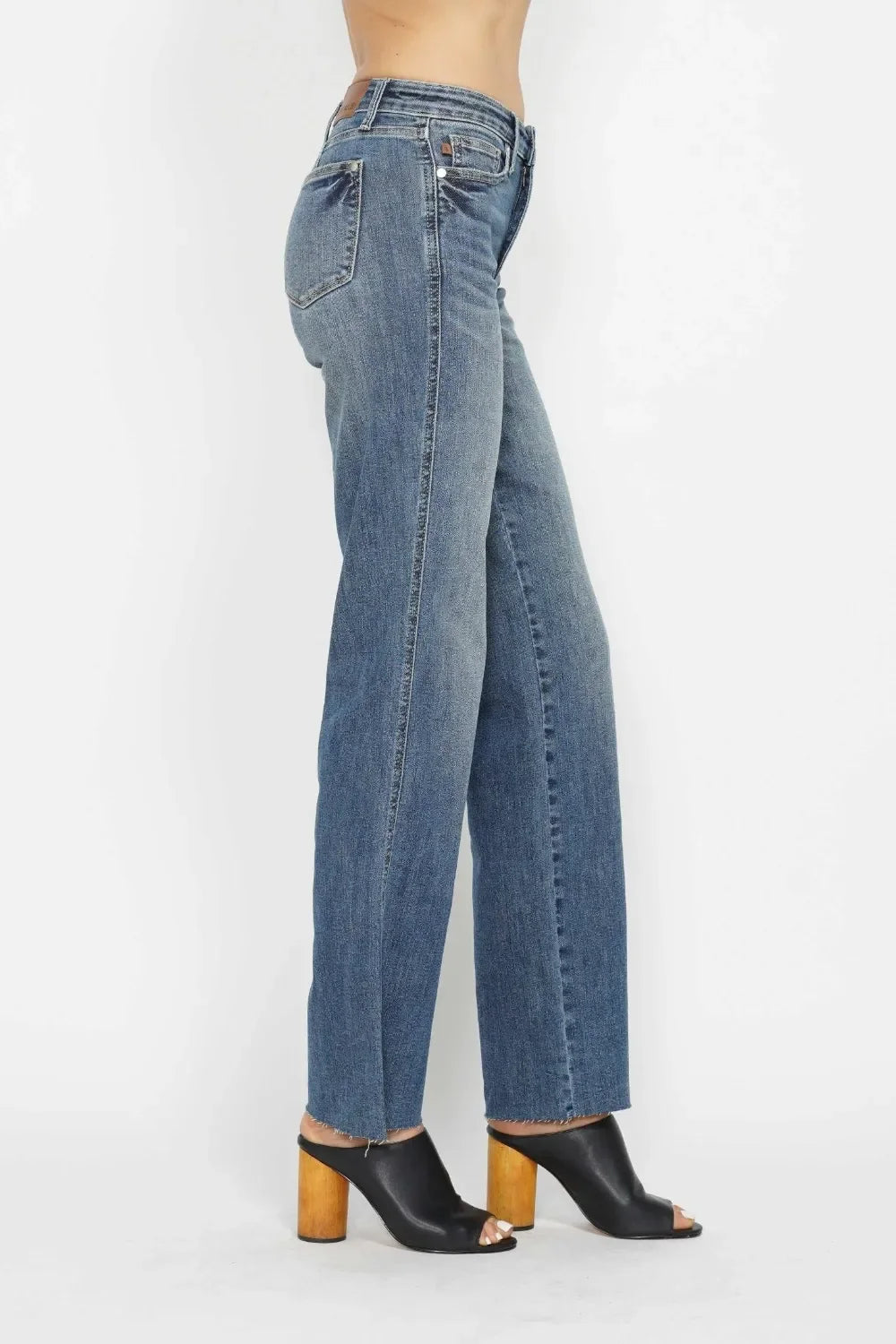 Straight leg blue jeans styled with black open-toe heeled mules on model