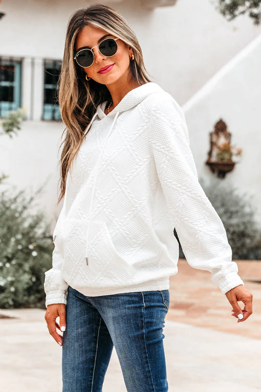 Woman wearing a textured white hoodie with drawstrings and blue jeans outdoors