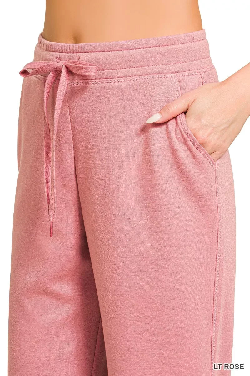 Close-up of pink drawstring lounge pants with pockets, relaxed fit, light rose color.
