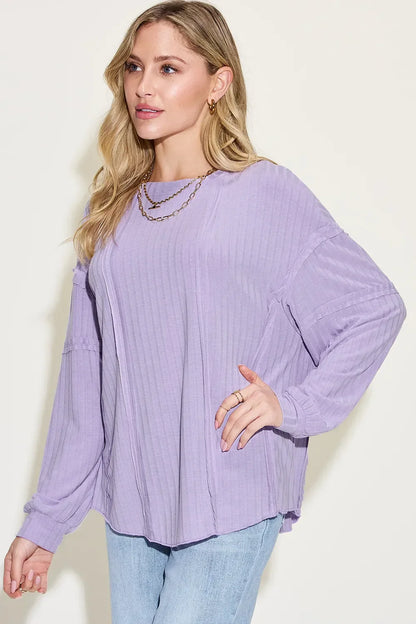 Woman wearing a relaxed-fit lavender ribbed long sleeve top with light wash jeans.