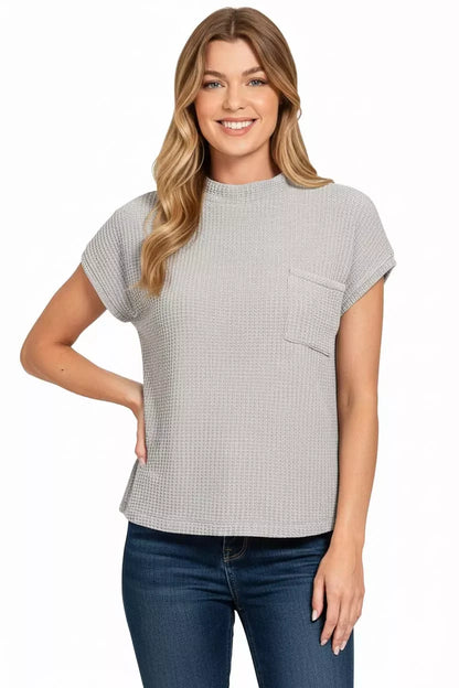 Woman wearing a textured short sleeve grey waffle knit top with chest pocket and blue jeans