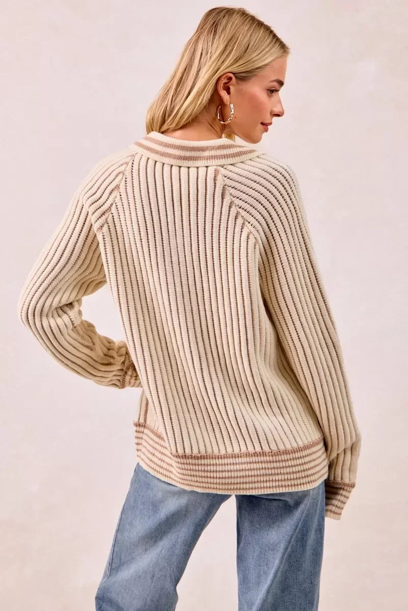 Woman wearing a cream ribbed knit sweater with relaxed fit and light blue denim jeans