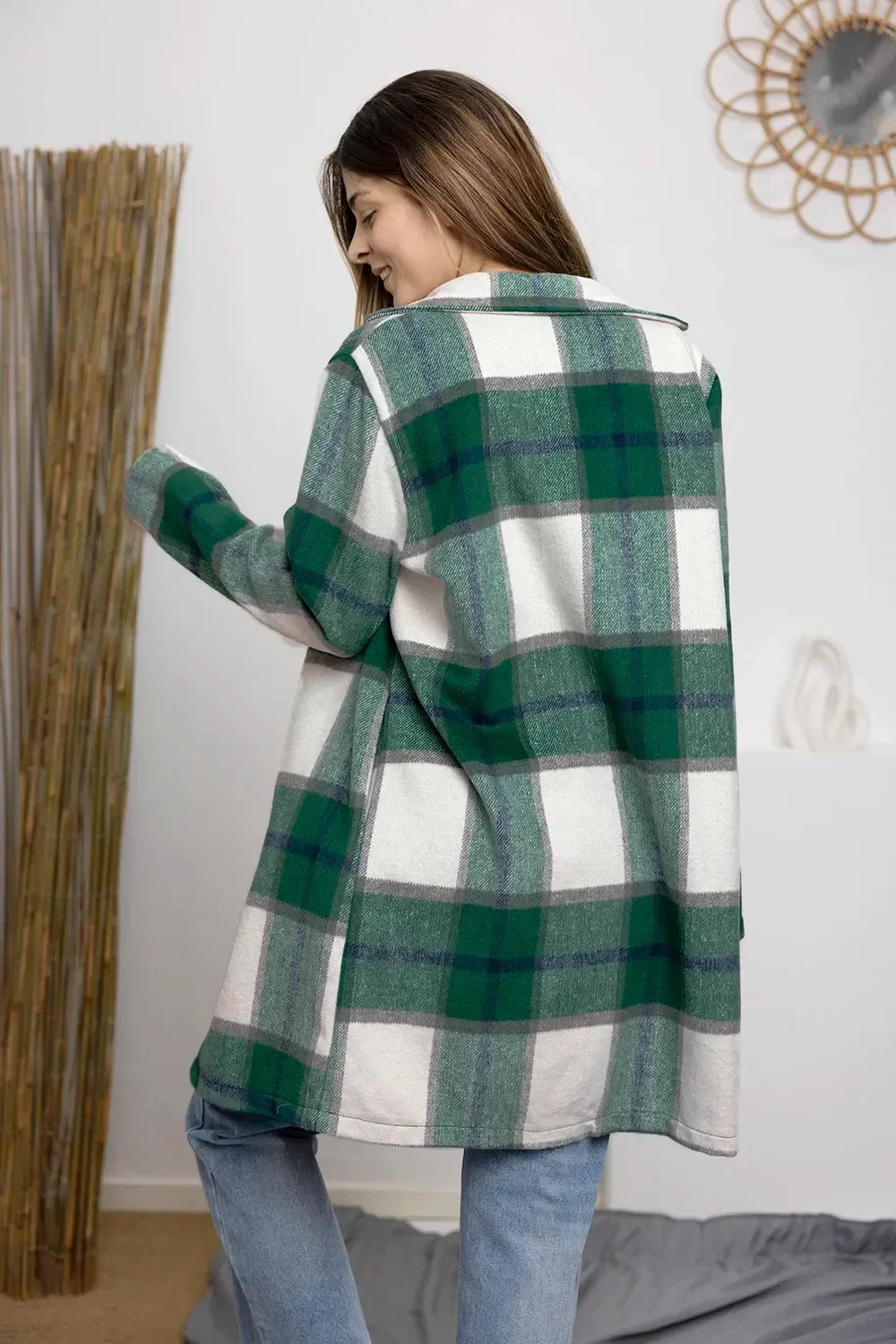 Woman wearing an oversized green plaid shacket with relaxed fit and light blue jeans.