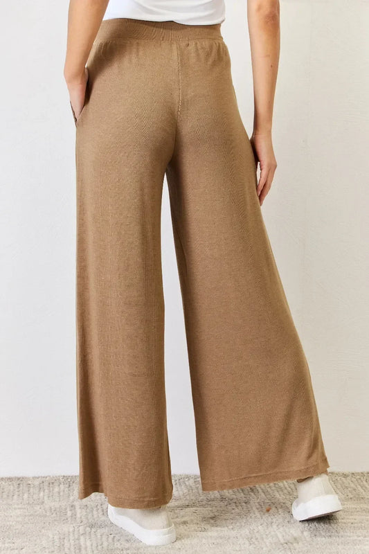 Woman wearing relaxed fit, tan wide-leg knit pants with side pockets