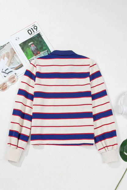 Back view of a long sleeve cream sweater with blue and red horizontal stripes, laid flat.