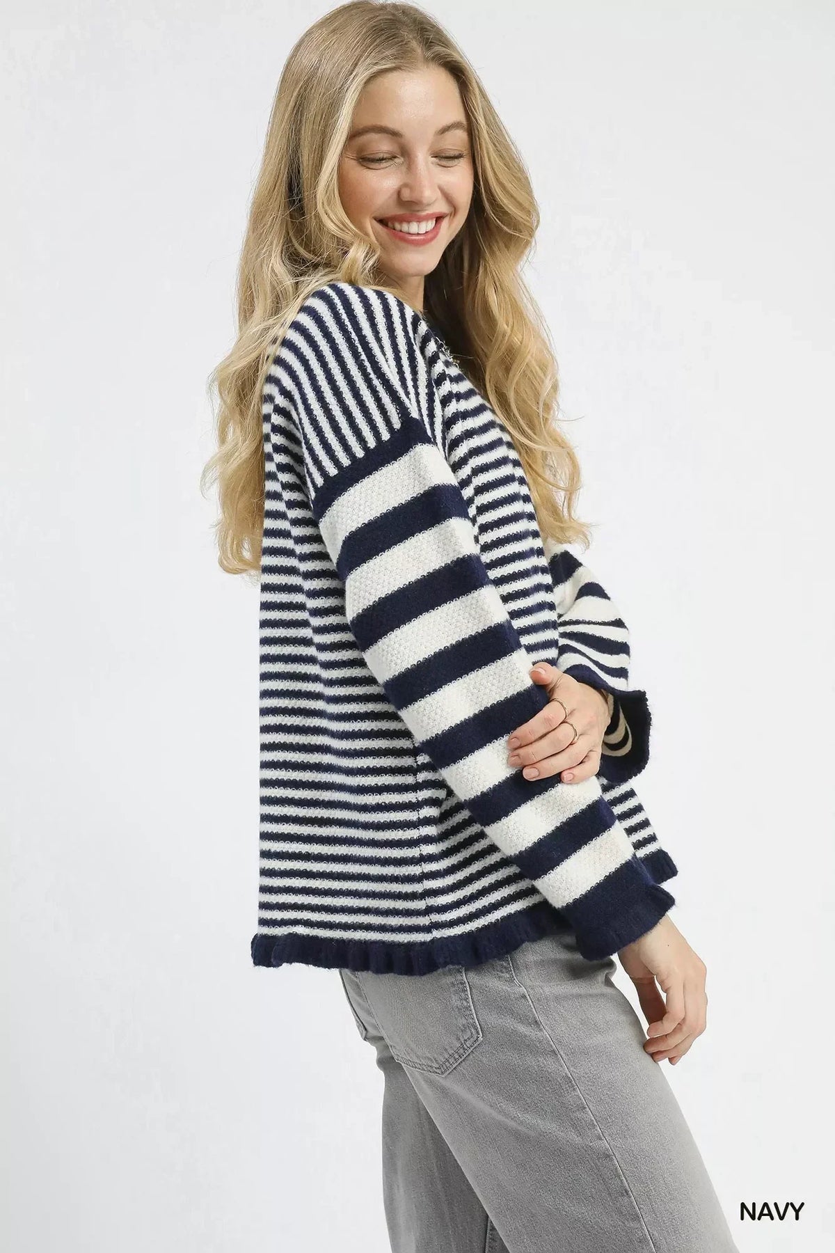 Woman wearing a navy and white striped knit sweater with relaxed fit and grey jeans