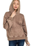 Woman wearing a brown oversized hooded sweatshirt with kangaroo pocket and jeans