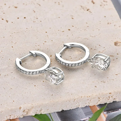 Silver hoop earrings with pavé cubic zirconia and oval crystal drops on stone surface