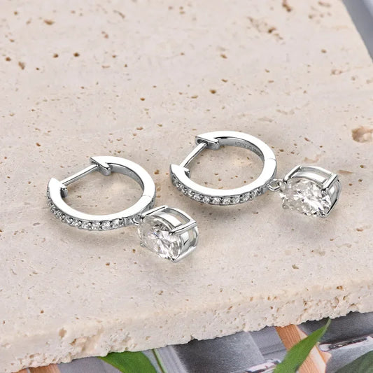 Silver hoop earrings with pavé cubic zirconia and oval crystal drops on stone surface