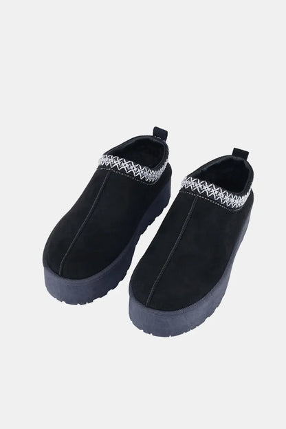Black slip-on platform shoes with white woven trim and thick rubber soles, displayed on white background.