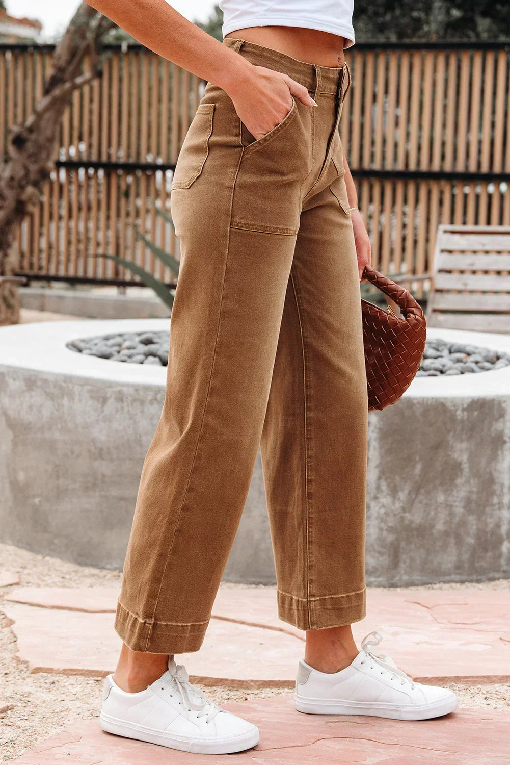 Woman wearing high-waisted tan wide-leg pants with pockets and white sneakers outdoors