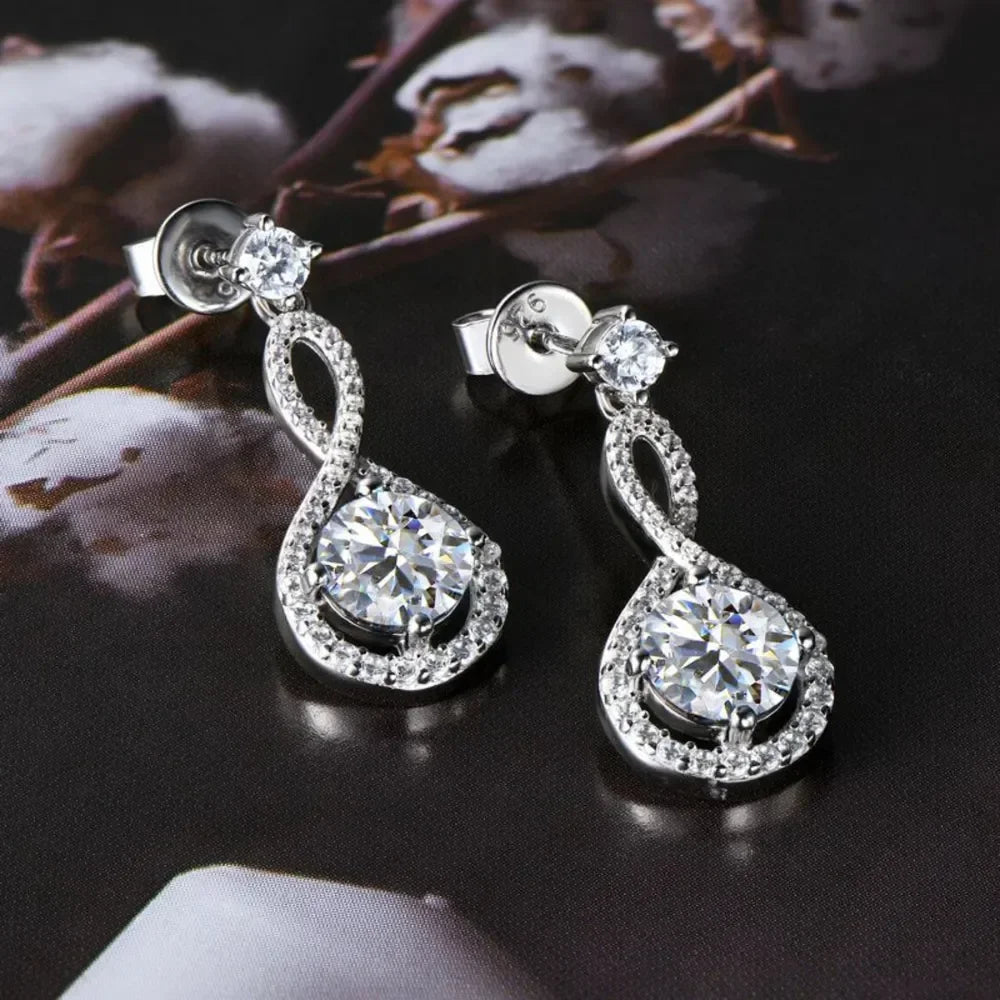 Silver drop earrings with sparkling round gemstones and pavé accents on a dark background